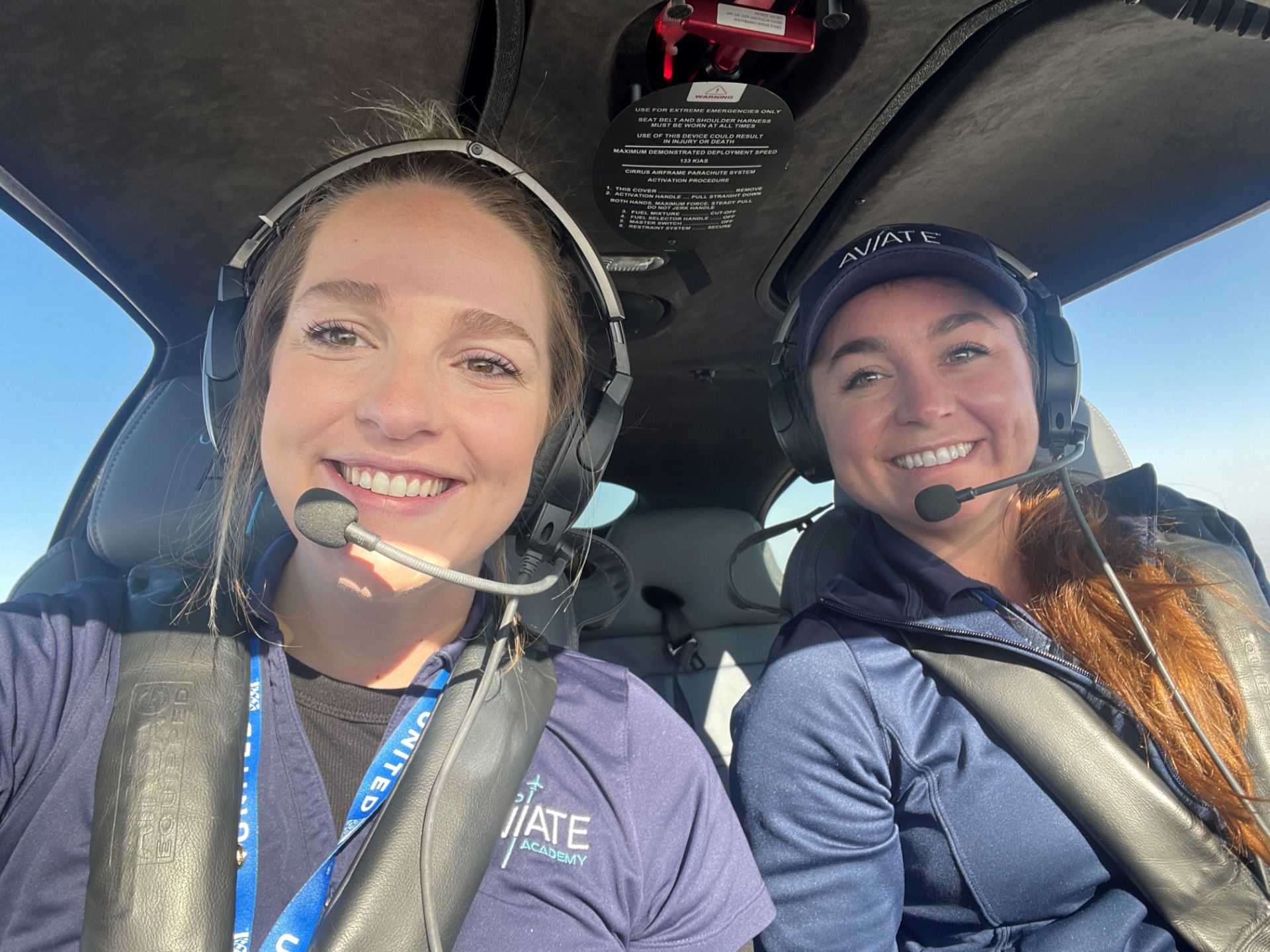 Two women flying a plane and smiling.