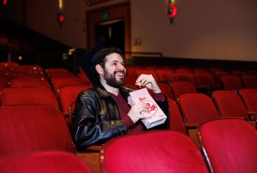 student eating popcorn in a dark movie theater