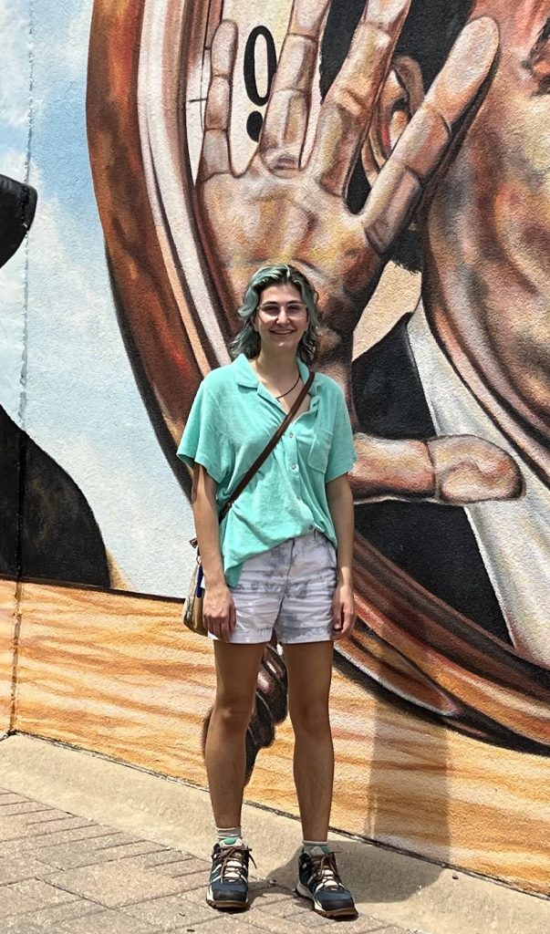 woman posed on a street in front of a mural 