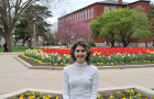 Allison Thabit standing in front of a bed of flowers on the quad.