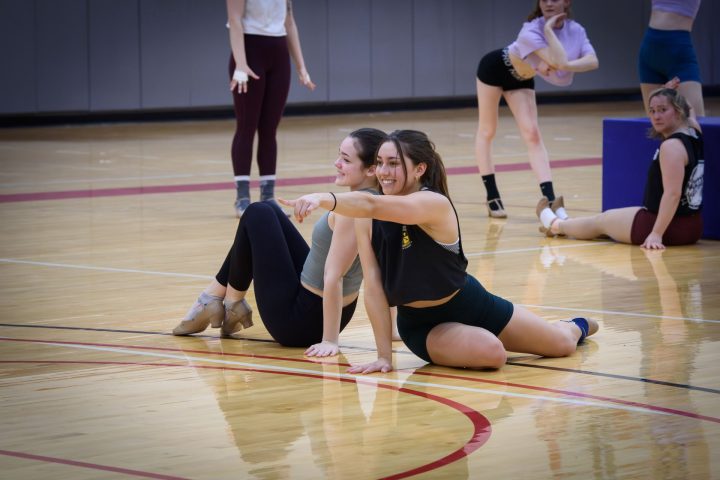 Two Gamma Phi Circus members are on the floor posing and pointing during a dance number.