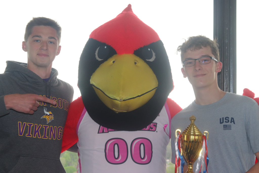 Two people pose for a photo with a Redbird mascot.