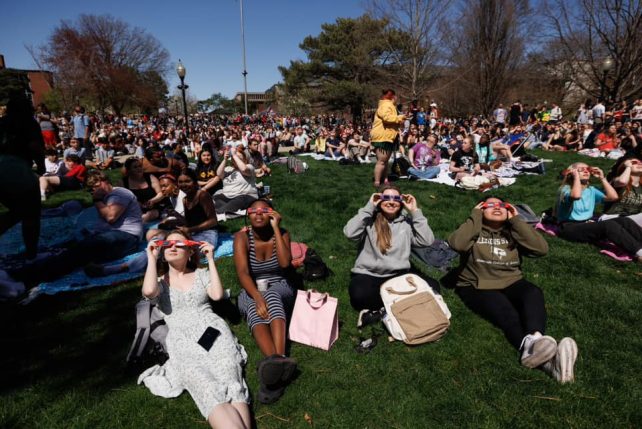 Students wearing eclipse glass watch the solar eclipse