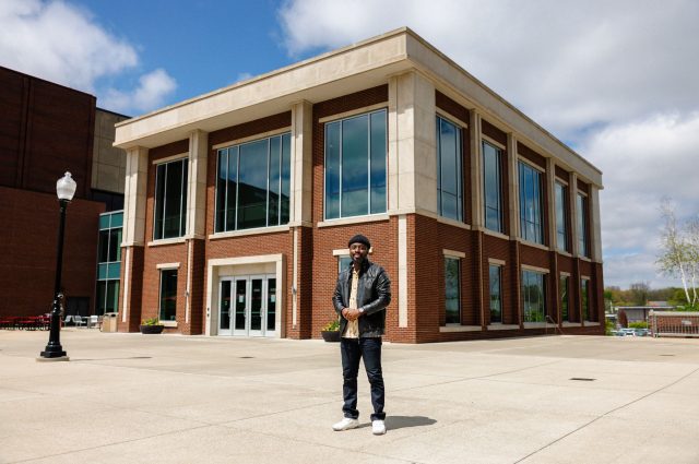 student in front of campus building