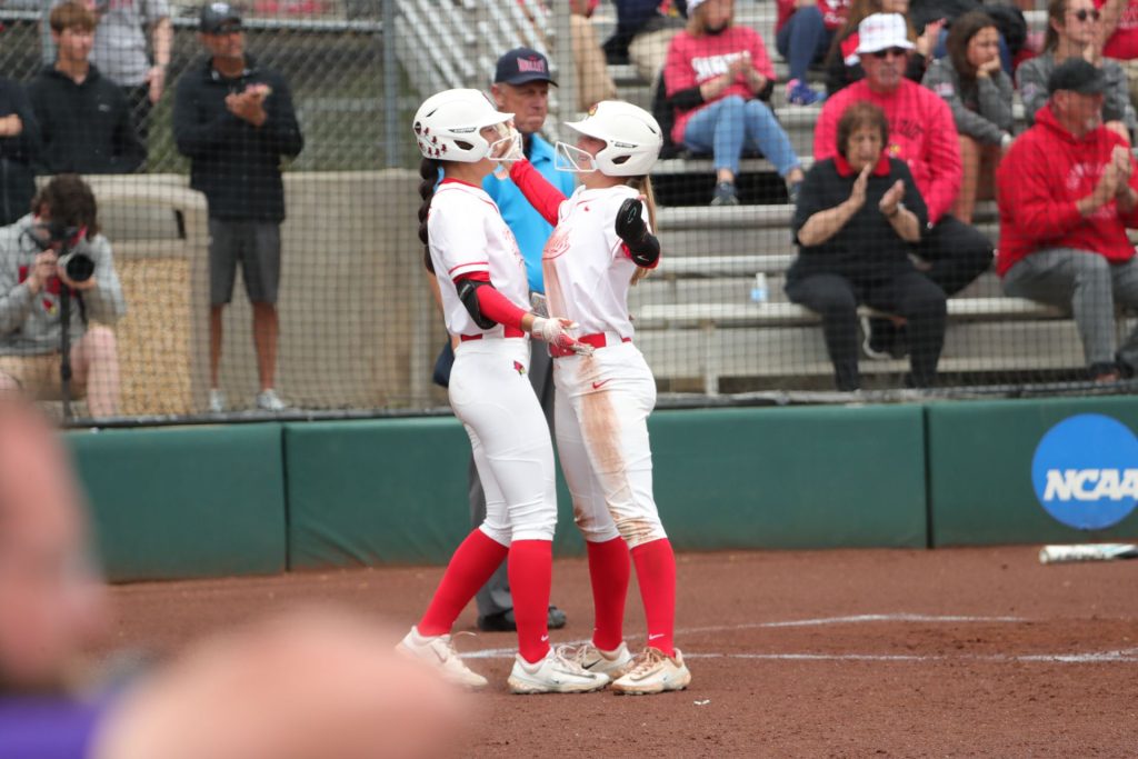 Two softball players celebrate at home plate