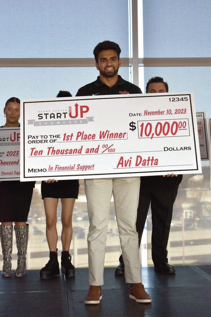 Aneel Gillan holding an oversized check after winning the Startup Showcase. 