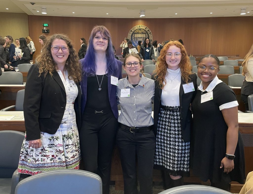 Five women posed at a conference