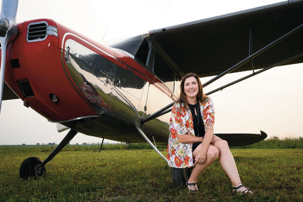 Laura Benton sitting on the step of a taildragger, a type of aircraft