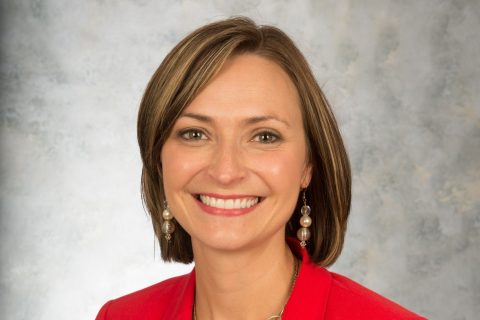 Head and shoulders image of a woman in a red blazer