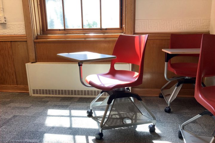A lone chair in a classroom in Williams Hall illuminated by sunlight through the window.