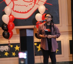 Writers Never Die group member and Simeon High School student Kendall Roberts performs her piece for a crowd at John Cook Elementary School. 