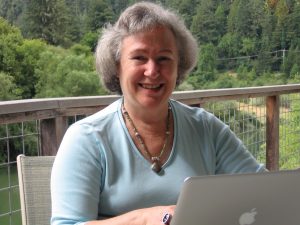 Joan Lippincott sitting on deck in front of laptop