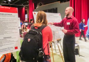 Photo of a student explaining research at the University Research Symposium. 