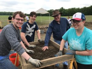 Dean Simpson assists students in sifting material at the archaeological site.