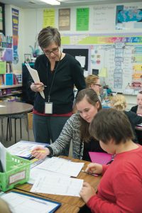 Deborah MacPhee (standing) developed an embedded course where Professional Development School interns, classroom teachers, and administrators explore literacy practices together. 