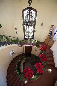 winding stairwell covered in garland and poinsettias