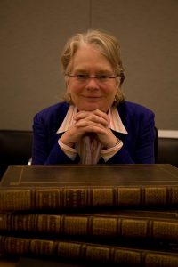 Historian Lynn Hunt with her head propped on her folded hands behind a stack of books