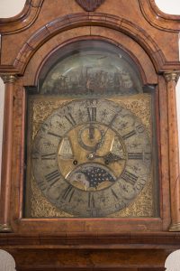 face of a clock with intricate metalwork in the shapes of masted ships.