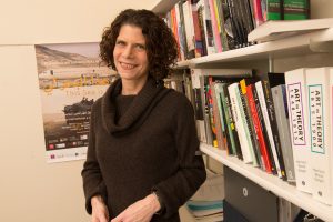 Associate Professor Elisabeth Friedman standing in front of shelves of books