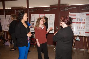 Three people discussing the work at the at the University Research Symposium