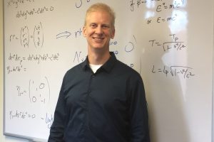 Professor Neil Christensen standing in front of board with equations on it