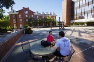Two students sit and talk on Illinois State University's Quad.