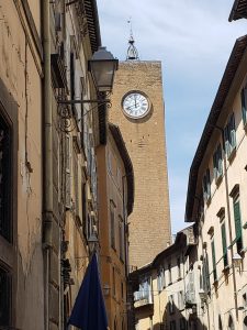 An alley in Orvieto with a clocktower emerging from the surrounding buildings