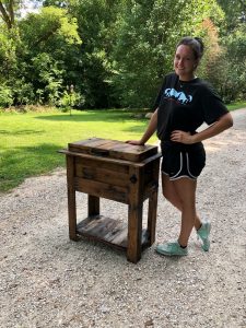 Kendra Cranford with wooden furniture outside