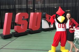 Girl with redbird mascot in front of big ISU letters