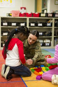 Cadet Isabella Diez, a junior at Illinois State, helps one of her first grader friends with a bracelet during the ROTC’s weekly Cadets Helping Kids visit at Unit 5’s Fox Creek Elementary School in Bloomington.
