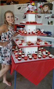 A Future Redbird poses with their red and white graduation cupcake display