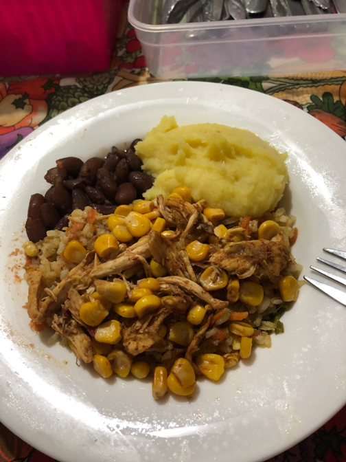 A dinner containing chicken, corn, rice, mashed potatoes and black beans