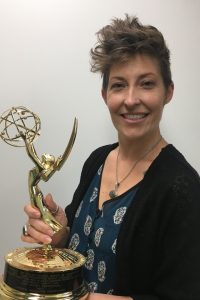 woman holding Emmy statuette.