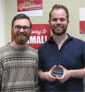 Two men, one holding an award
