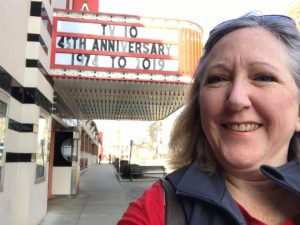 TV-10 News Director Laura Trendle Polus in front of TV-10 anniversary movie marquee