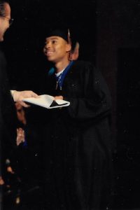 man in graduation attire grabbing diploma
