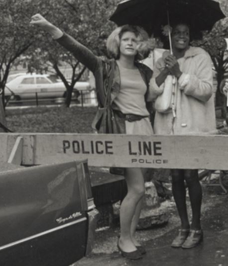Two women behind a barrier that reads Police Line