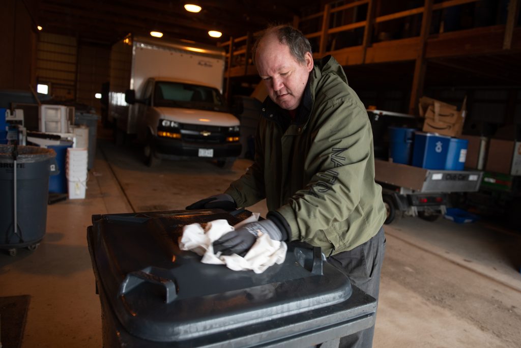 Man sanitizes recycling bin