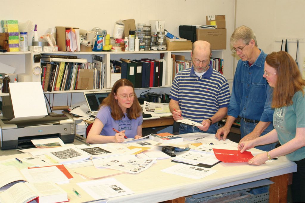 four people collaborating on a book project around a table