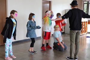 Students wearing paper theatrical masks while participating in a creative drama class in 2019