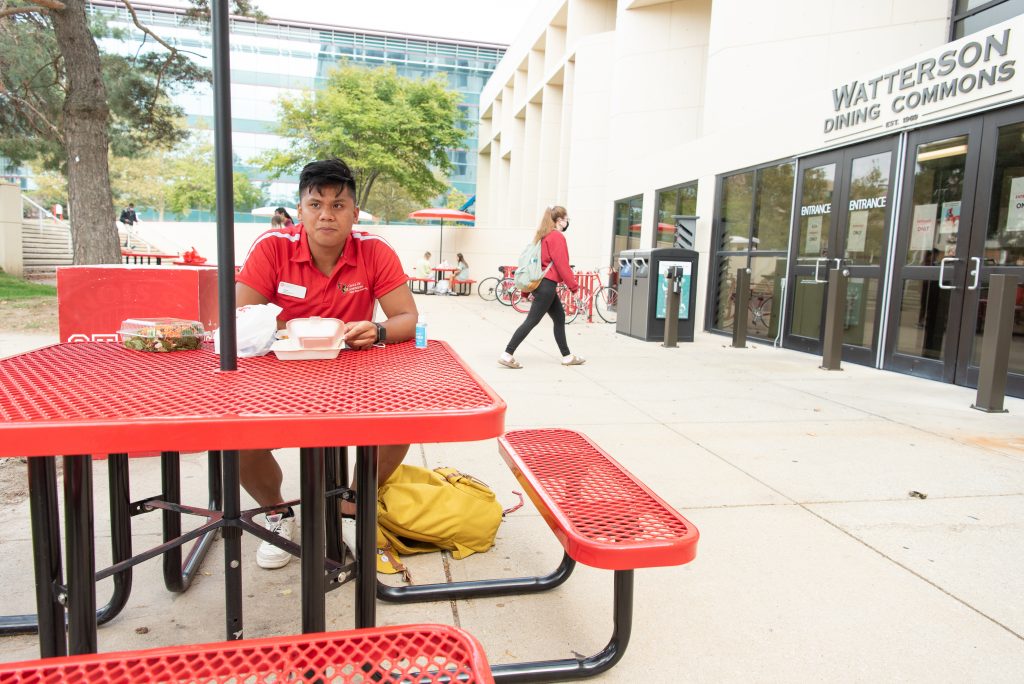 Micor eats lunch at a picnic table outside of the Watterson Dining Commons.
